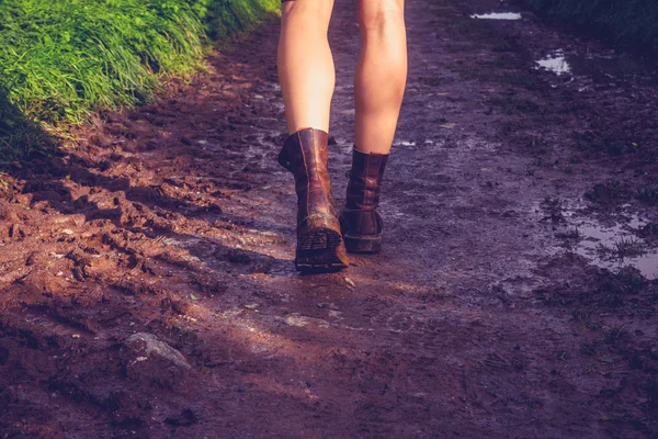 Young woman walking along muddy trail — Stock Photo, Image