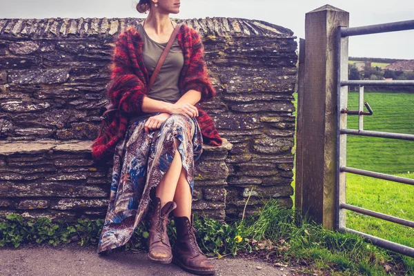 Frau entspannt sich an ländlicher Steinmauer — Stockfoto