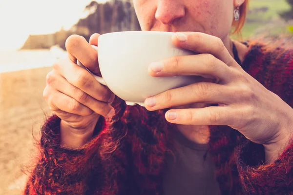 Woman drinking coffee by the sea — Stock Photo, Image