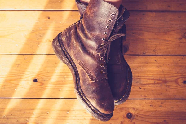 Pies de mujer en botas de cuero sobre piso de madera — Foto de Stock