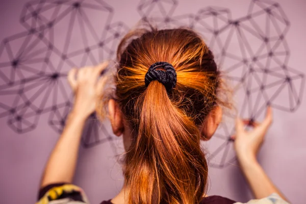 Mujer joven colgando una obra de arte en su pared — Foto de Stock