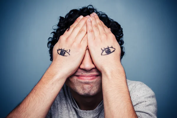 Hombre con ojos pintados en sus manos — Foto de Stock