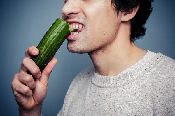 Jovem mordendo um pepino — Fotografia de Stock