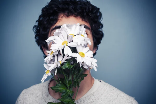 Young man hiding behind flowers — Stock Photo, Image