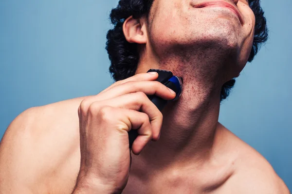 Чоловік голиться з електричною бритвою — стокове фото