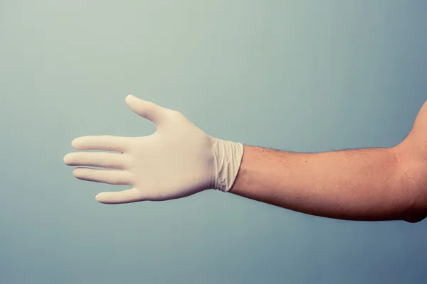 Hand wearing latex glove offering handshake — Stock Photo, Image