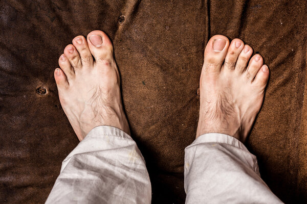 Man's bare feet on brown texture