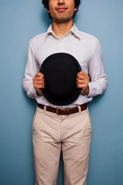 Jovem sorridente segurando um chapéu de jogador — Fotografia de Stock