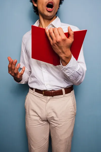 Jovem segurando um livro e cantando — Fotografia de Stock