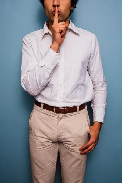 Young man gesturing hush with finger on lips — Stock Photo, Image