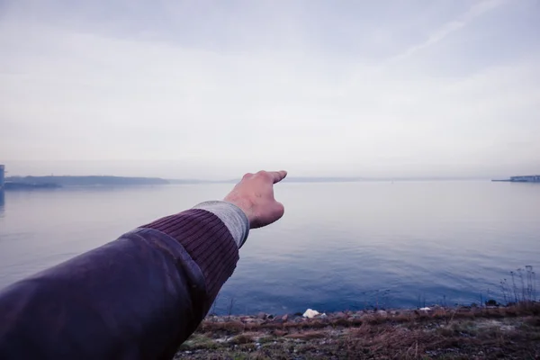 A mão do homem apontando para o horizonte e à beira-mar — Fotografia de Stock