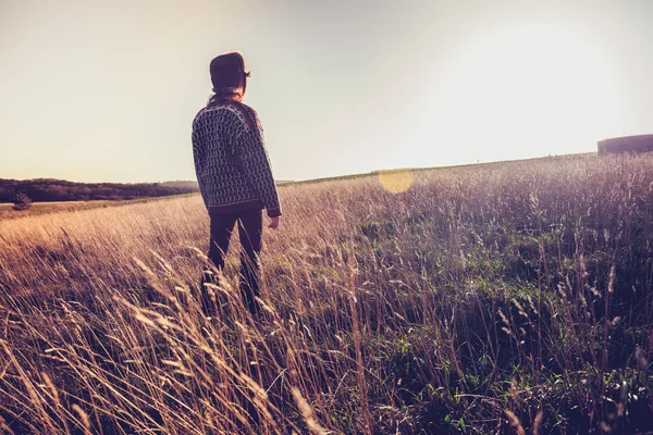 Jeune femme regardant le coucher du soleil dans la prairie — Photo