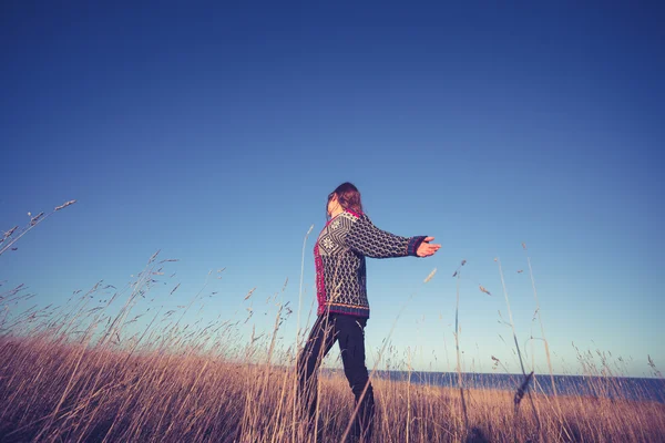Молодая женщина выражает свободу в поле на закате — стоковое фото