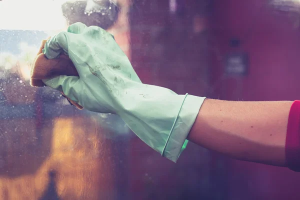 Hand mit Gummihandschuh putzt Fenster — Stockfoto