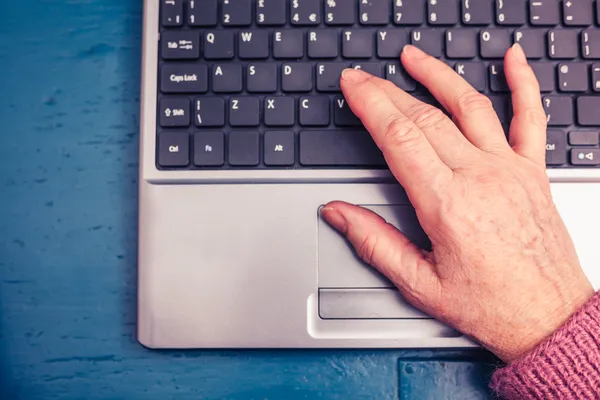 Oude vrouw die op laptopcomputer thuis werkt — Stockfoto