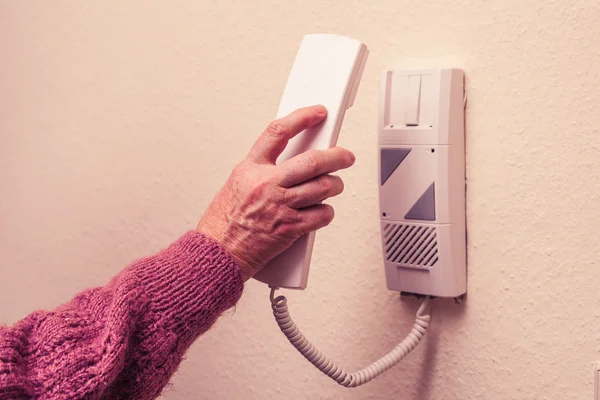 Old woman answering intercom — Stock Photo, Image