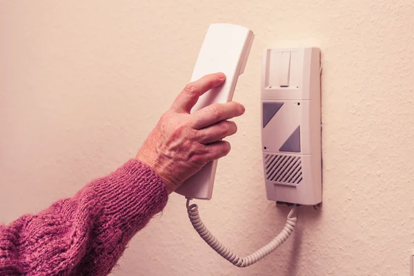 Alte Frau antwortet auf Gegensprechanlage — Stockfoto