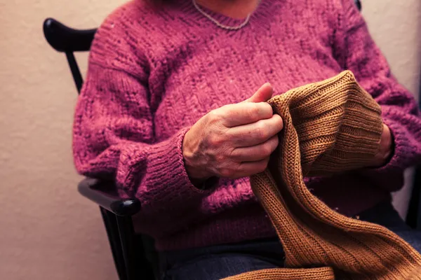 Stará žena zašívání jumper doma — Stock fotografie