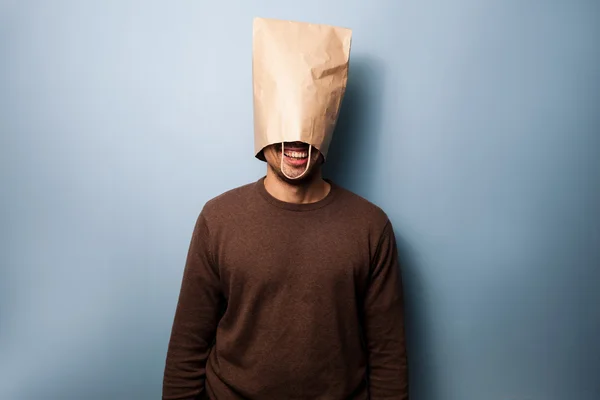 Happy young man with a bag over his head — Stock Photo, Image