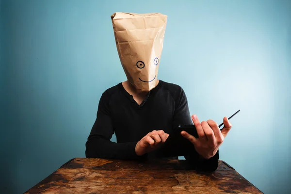 Человек с мешком на голове с помощью планшетного компьютера — стоковое фото