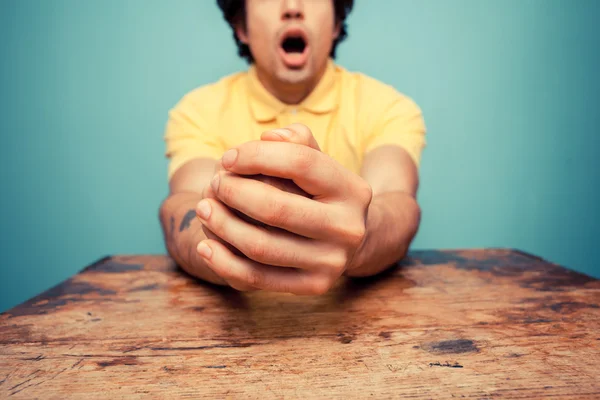 Joven con las manos dobladas mirando sorprendido — Foto de Stock