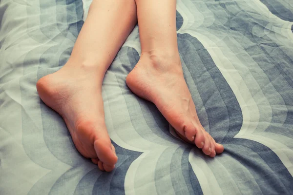 Stopy młode kobiety na łóżko w domu — Zdjęcie stockowe