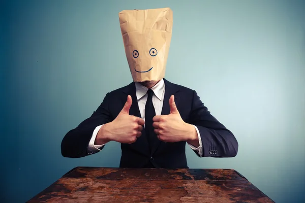 Businessman with bag over head giving thumbs up — Stock Photo, Image