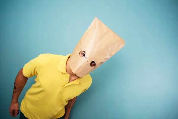 Junger Mann mit Tasche über dem Kopf blickt in Kamera — Stockfoto