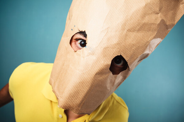 Young man with bag over head looking at camera