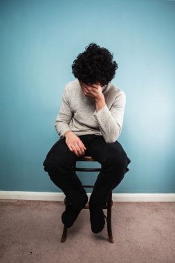 bir sandalyede oturan üzgün bir adam