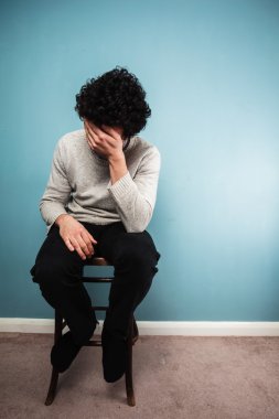 bir sandalyede oturan üzgün bir adam