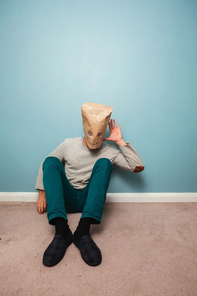 Man with bag over head on floor is listening — Stock Photo, Image
