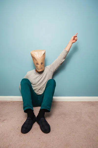 Man with bag over head on floor is pointing — Stock Photo, Image