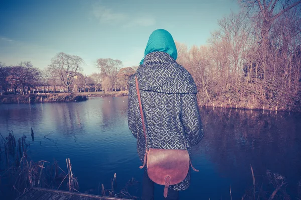 Молодая женщина за прудом осенью — стоковое фото