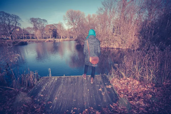 Jovem mulher por lagoa no outono — Fotografia de Stock