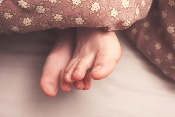 Pies de mujer en la cama — Foto de Stock