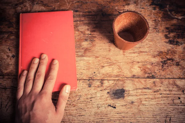 Hand, boek en leer dobbelstenen cup — Stockfoto