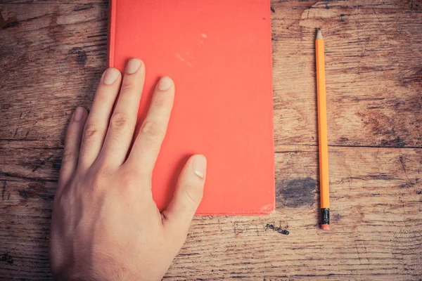 Hand met boek en potlood — Stockfoto