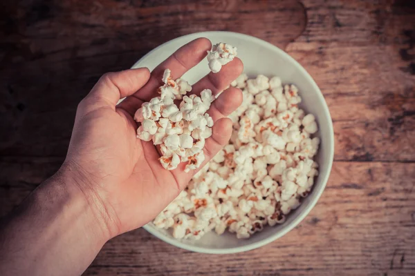 Hand holt Popcorn aus Schüssel — Stockfoto