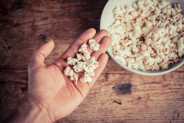 Hand holt Popcorn aus Schüssel — Stockfoto