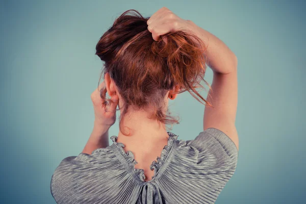 Jovem mulher ajustando seu cabelo — Fotografia de Stock