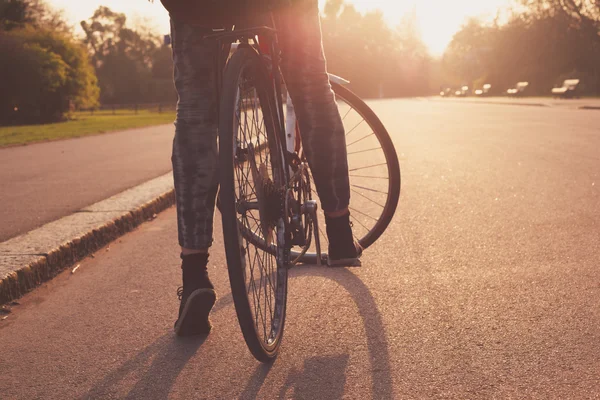 Jeune femme faisant du vélo dans le parc au coucher du soleil — Photo