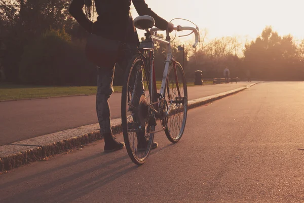 Ung kvinna med cykel i parken — Stockfoto