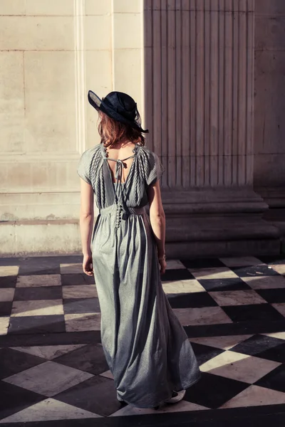 Elegant young woman standing in a grand hall — Stock Photo, Image