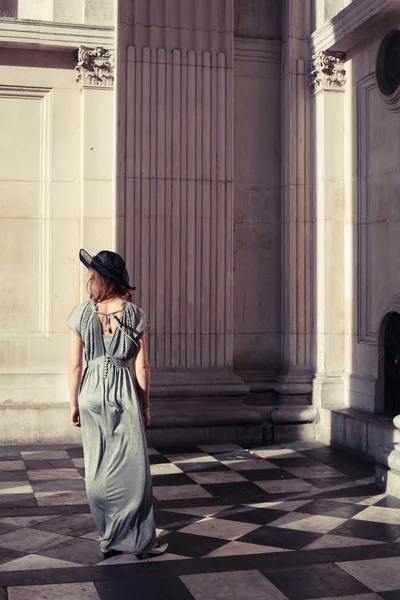 Elegant young woman standing in a grand hall — Stock Photo, Image