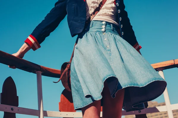Молодая женщина на палубе корабля с юбкой, дующей на ветру — стоковое фото