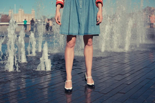 Молода жінка стоїть біля фонтану в місті в спекотний день — стокове фото