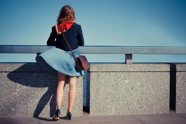 Young woman standing on bridge with her skirt blowing — Stock Photo, Image