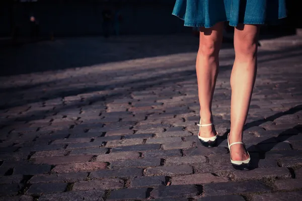 Young woman in skirt walking on a cobbled street — Stock Photo, Image