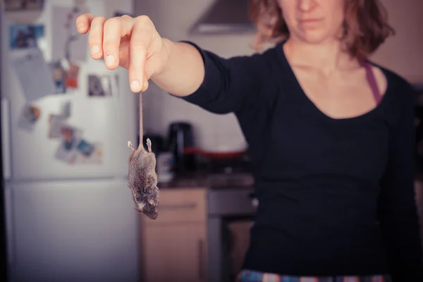 Woman holding a dead mouse in her kitchen — Stock Photo, Image